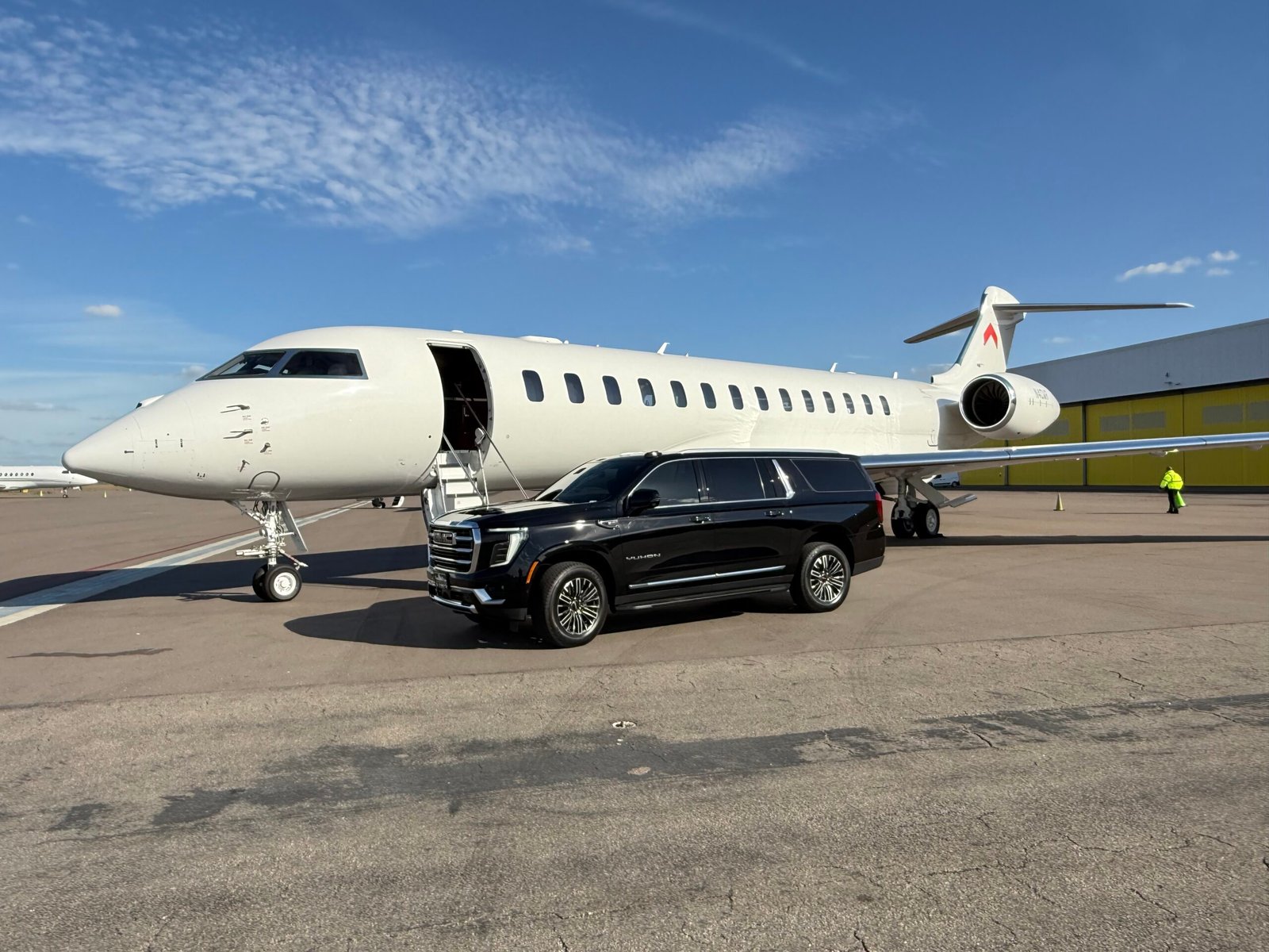 Black GMC Yukon SUV beside a private jet on the Tampa tarmac — Champa Bay Limo airport car service